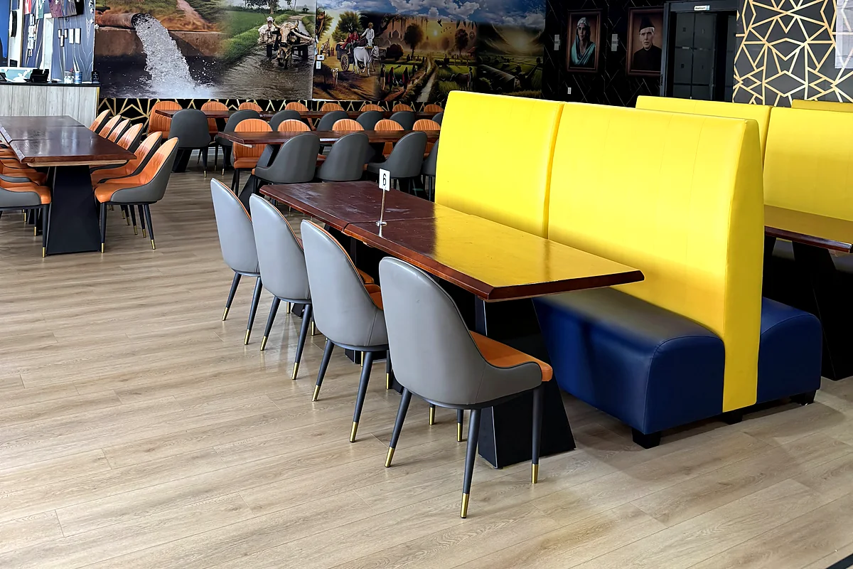 Dining room with yellow booth seating, grey chairs and wooden tables