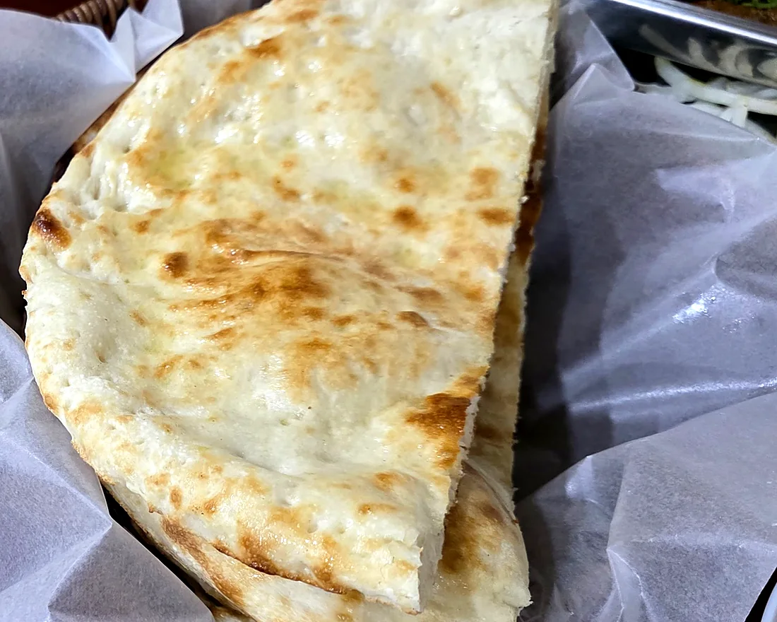 Freshly baked naan folded in a paper-lined basket